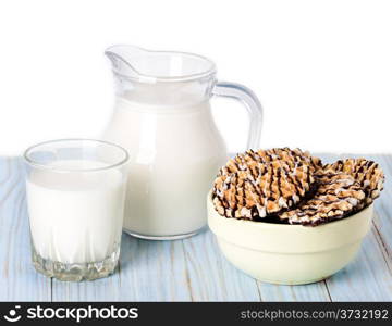 Composition milk in a jug, a glass and cookies on blue wooden background