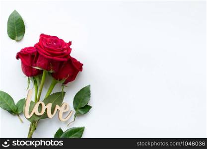 Composition of bouquet of red roses and decorative wooden word love on white background . Happy Valentines Day. Top view. Space for text. Copyspace. Space for text.. Composition of bouquet of red roses and decorative wooden word love on white background . Happy Valentines Day. Top view. Space for text. Copyspace