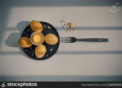 Composition of Broken fresh chicken egg (Hen egg) put at the middle of the fresh eggs with brown eggshell and Black antique silver fork on white table. Natural organic healthy food concept, Top view, Copy space. Selective focus.