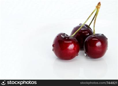 Composition of bunch of sweet cherries on a white plate isolated closeup on white background with clipping path. Ripe cherries with peduncles lies.