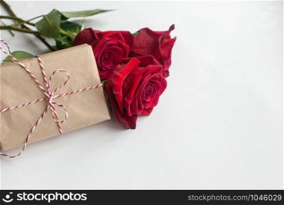 Composition of gift and bouquet of red roses on white background . Happy Valentines Day. Top view. Space for text. Copyspace. Composition of gift and bouquet of red roses on white background . Happy Valentines Day. Top view. Space for text.