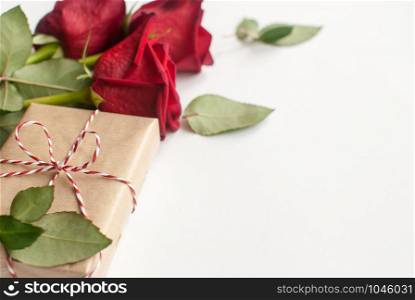 Composition of gift and bouquet of red roses on white background . Happy Valentines Day. Selective focus. Top view. Space for text. Copyspace. Composition of gift and bouquet of red roses on white background . Happy Valentines Day. Top view. Space for text. Selective focus