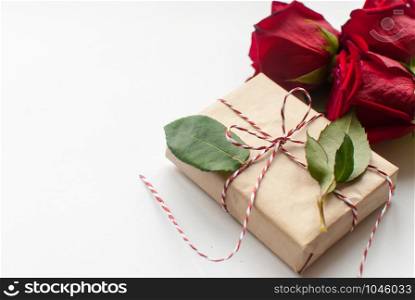 Composition of gift and bouquet of red roses on white background . Happy Valentines Day. Top view. Space for text. Copyspace. Composition of gift and bouquet of red roses on white background . Happy Valentines Day. Top view. Space for text.