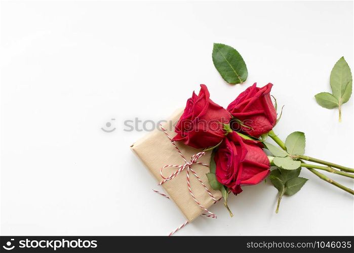 Composition of gift and bouquet of red roses on white background . Happy Valentines Day. Top view. Space for text. Copyspace. Composition of gift and bouquet of red roses on white background . Happy Valentines Day. Top view. Copyspace