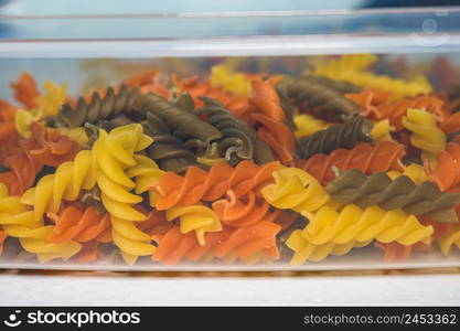 Composition of raw pasta uncooked tricolore fusilli, pasta twist shape. Close up and selective focus on colorful fusilli pasta.