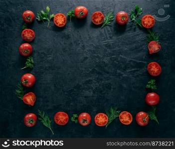 Composition of red tomatoes and green fresh parsley and dill lying on dark background in form of frame. Vegeterian food concept. Free space in middle