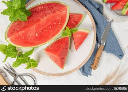 Composition of ripe watermelon and fresh mint on the kitchen table. Ripe summer watermelon. Juicy watermelon. Concept of seasonal fruits on the table