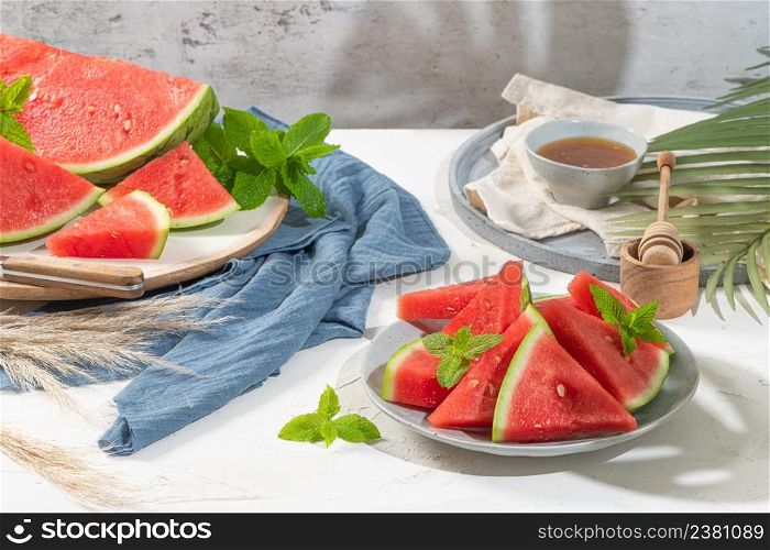 Composition of ripe watermelon and fresh mint on the kitchen table. Ripe summer watermelon. Juicy watermelon. Concept of seasonal fruits on the table