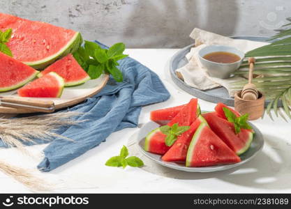 Composition of ripe watermelon and fresh mint on the kitchen table. Ripe summer watermelon. Juicy watermelon. Concept of seasonal fruits on the table