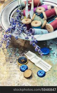 Composition of the threads and lavender. Set of buttons and thread on a background of cut branches of lavender.