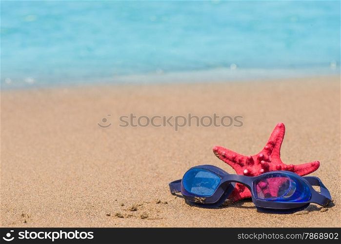 composition on the beach with goggles for swimming and starfish