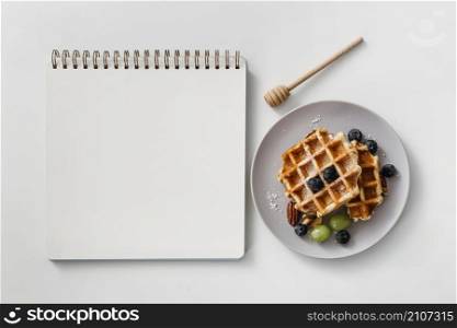 composition tasty breakfast waffles with empty notebook