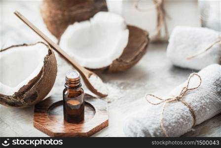 Composition with coconut oil in a bottle and fresh coconut on a light background, spa therapy concept. Composition with coconut oil and fresh coconut