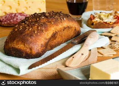 Composition with crusty bread, yellow cheese, butter, salami and red wine