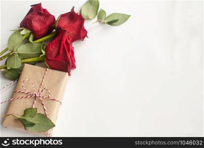 Composition with gift and bouquet of red roses on white background . Happy Valentines Day. Top view. Space for text. Copyspace. Composition with gift and bouquet of red roses on white background . Happy Valentines Day. Top view. Space for text.