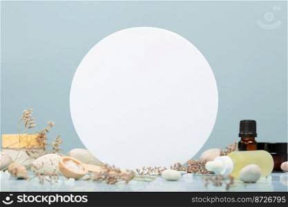 Composition with natural cosmetics on table with stones and flowers and Empty white circle podium on blue background. Bio organic spa and beauty products. Eco-friendly zero waste packaging