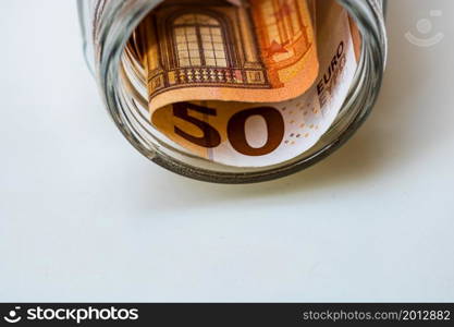 Composition with saving money banknotes (50 EURO) in a glass jar. Concept of investing and keeping money, close up isolated.