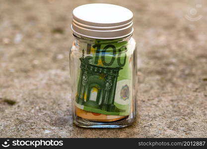 Composition with saving money banknotes in a glass jar. Concept of investing and keeping money, close up isolated.