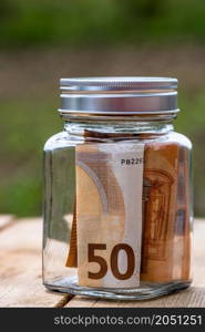 Composition with saving money banknotes in a glass jar. Concept of investing and keeping money, close up isolated.