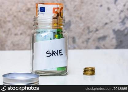 Composition with saving money banknotes in a glass jar with text save. Concept of investing and keeping money, close up isolated.