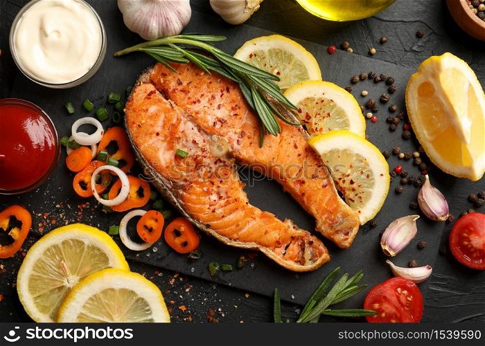 Composition with tasty grilled salmon on black background, top view