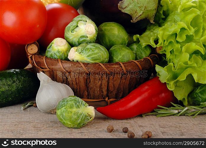 Composition with vegetables in wicker basket on wooden board