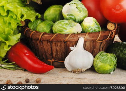 Composition with vegetables in wicker basket on wooden board