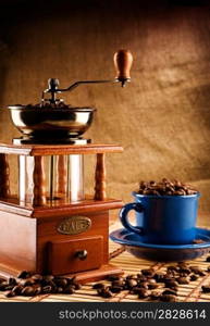 compositioon of grinder and coffee grains and blue mug