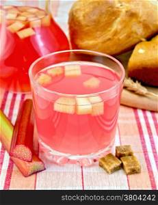 Compote from rhubarb in a glass and pitcher, rhubarb stalks, sugar, bread on tablecloth background
