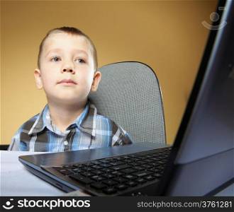 Computer addiction child boy with laptop notebook brown background