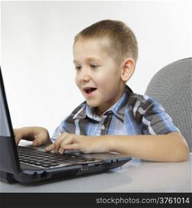 Computer addiction emotional child boy with laptop notebook playing games isolated on white background