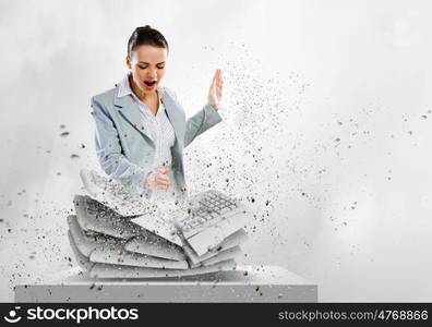 Computer addiction. Image of businesswoman crushing with hand pile of keyboards