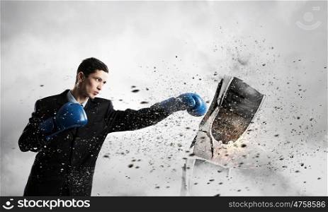 Computer break problem. Young businessman in blue boxing gloves breaking computer