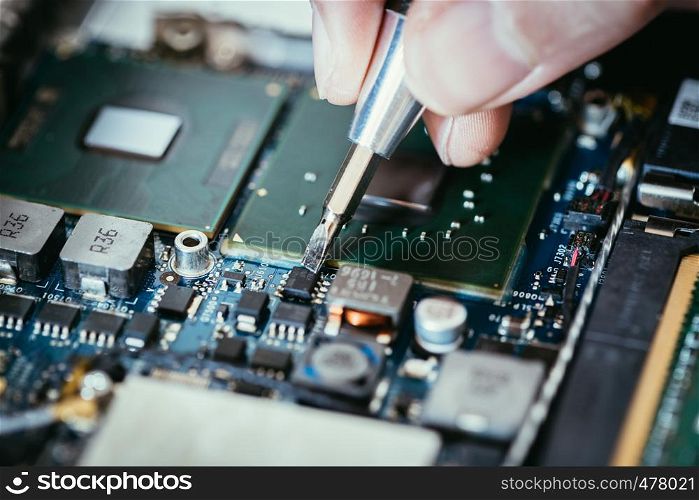 Computer circuit board, hand and screwdriver: Technician is fixing a motherboard.