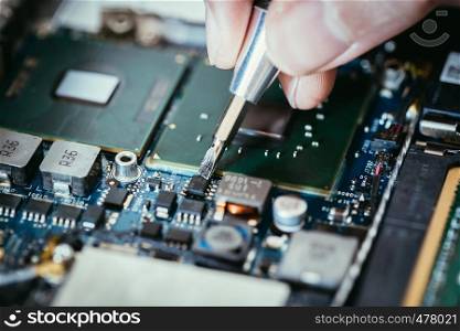 Computer circuit board, hand and screwdriver: Technician is fixing a motherboard.