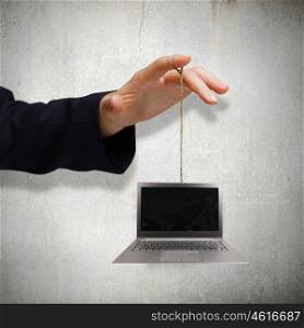 Computer concept. Close up of male hand holding laptop on rope