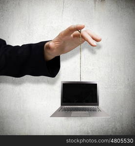 Computer concept. Close up of male hand holding laptop on rope