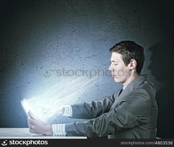 Computer generation. Young businessman looking seriously in tablet pc