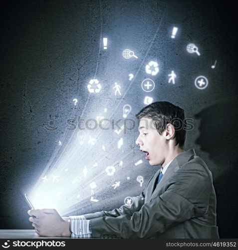 Computer generation. Young businessman looking surprised into tablet pc. Net and communication