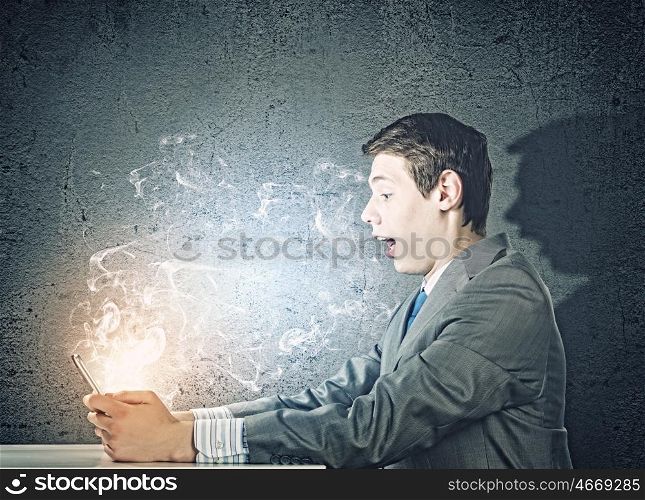 Computer generation. Young businessman looking surprised into tablet pc. Net and communication