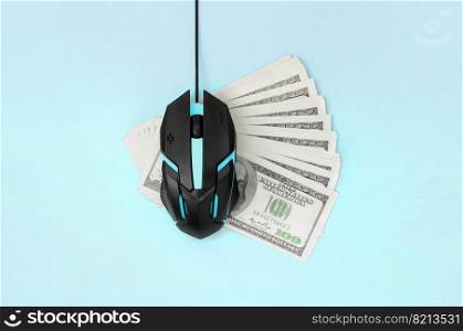 Computer mouse on many dollar bills. Pay per click and autoclicker concept. Earnings on the Internet. Flat lay top view on pastel blue background. Black computer mouse on many hundred dollar bills