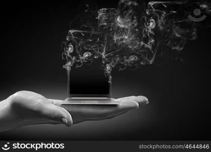 Computer problems. Human hand holding burning laptop on palm