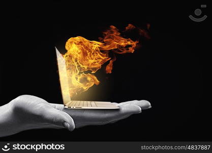 Computer problems. Human hand holding burning laptop on palm