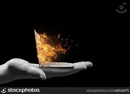 Computer problems. Human hand holding burning laptop on palm