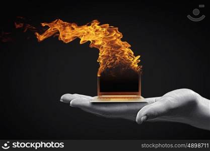Computer problems. Human hand holding burning laptop on palm