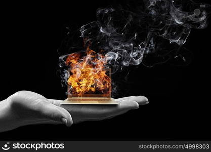 Computer problems. Human hand holding burning laptop on palm