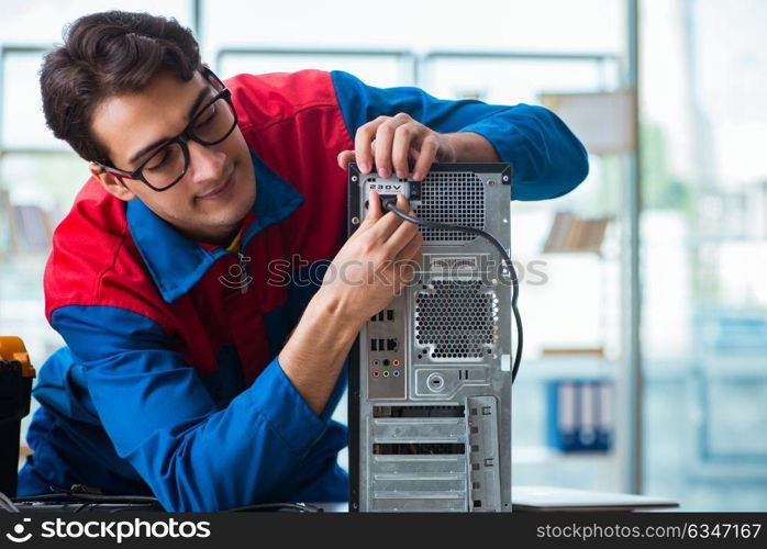 Computer repairman working on repairing computer in IT workshop. The computer repairman working on repairing computer in it workshop