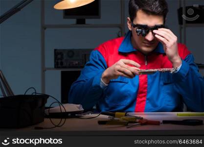 Computer specialist repairing PC late at night