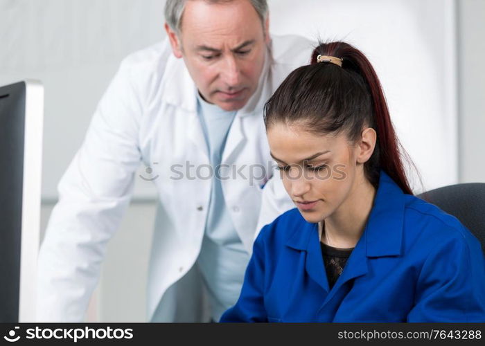 computer teacher helping pretty female student in his class