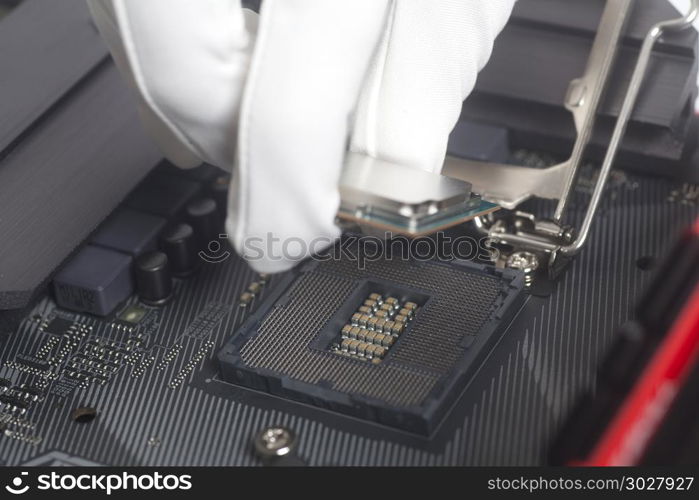 Computer technician wearing white gloves installing CPU into motherboard.. Computer technician wearing white gloves installing CPU into motherboard. Close up.